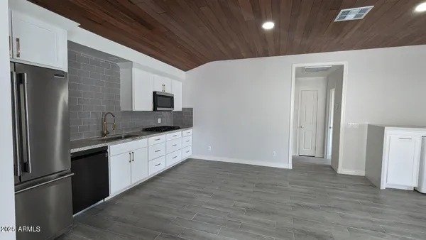 a large kitchen with stainless steel appliances granite countertop a refrigerator and a stove top oven
