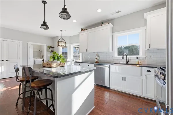 a kitchen with stainless steel appliances kitchen island a large white table chairs and a refrigerator