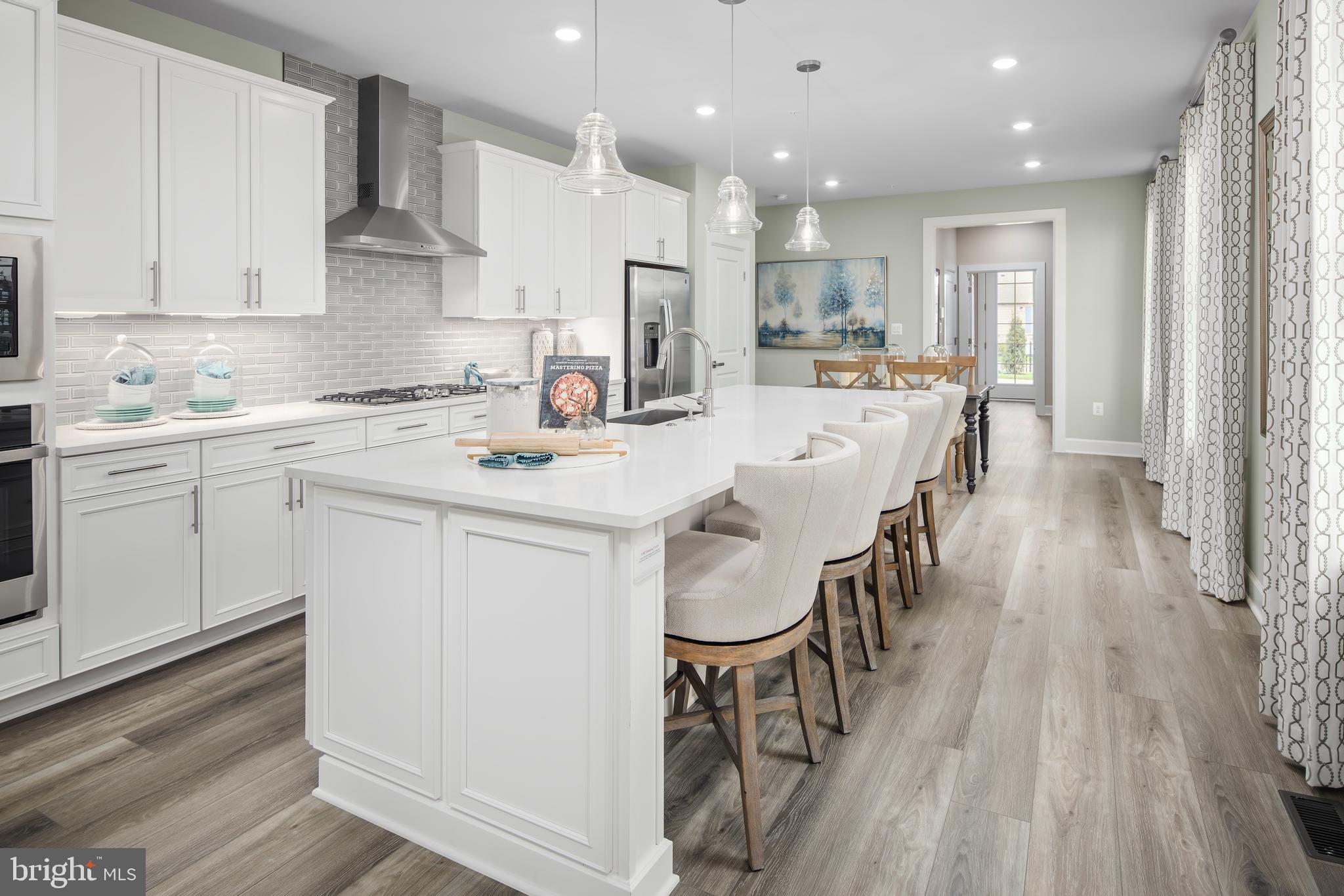 1 Mayapple Lane Frederick, MD 21702 - Photo 3 of 18 a kitchen with stainless steel appliances kitchen island granite countertop a stove a sink a refrigerator and white cabinets with wooden floor
