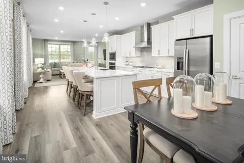 a kitchen with stainless steel appliances granite countertop a sink dishwasher a stove a refrigerator with a dining table and chairs