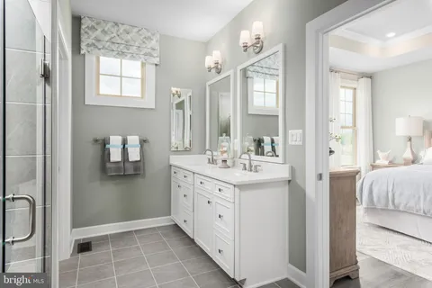 a spacious bathroom with a double vanity sink a mirror and a shower