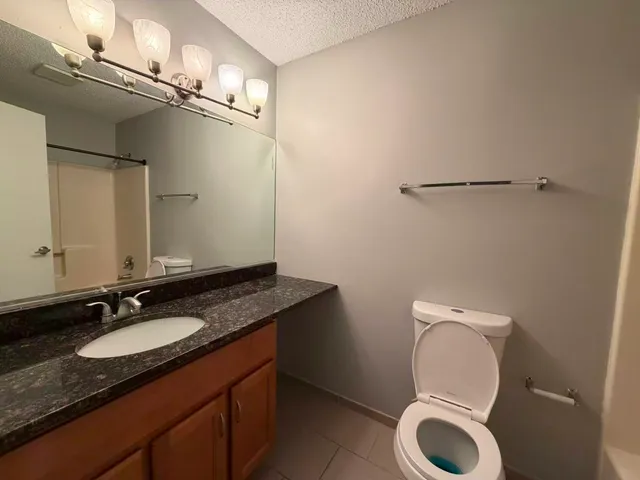 a bathroom with a granite countertop toilet sink and mirror