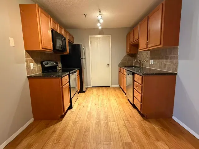 a kitchen with stainless steel appliances granite countertop a stove a sink and a refrigerator