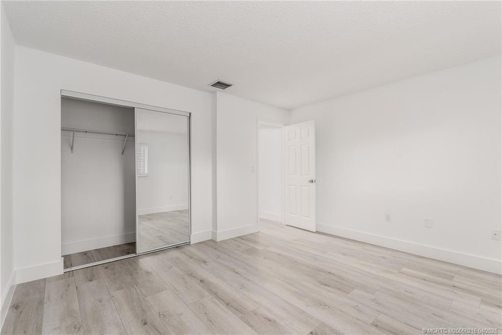 644 Southwest Cleveland Avenue, Unit 6 Stuart, FL 34994 - Photo 6 of 22 an empty room with wooden floor & closet and windows
