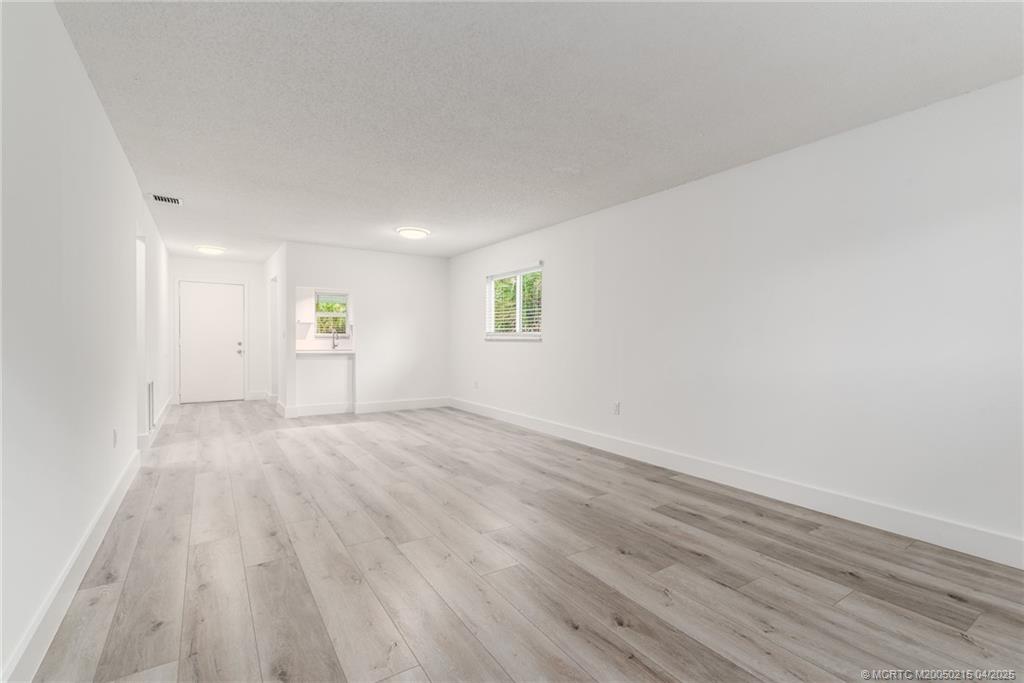 644 Southwest Cleveland Avenue, Unit 6 Stuart, FL 34994 - Photo 8 of 22 an empty room with wooden floor and windows