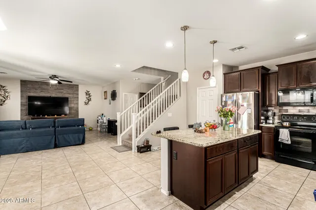 a kitchen with a stove a refrigerator and a flat screen tv