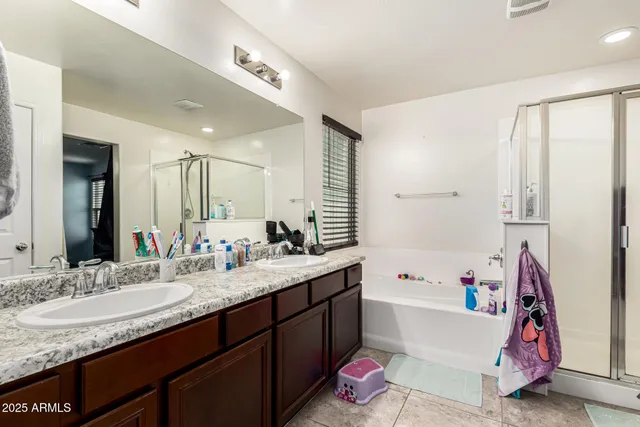 a bathroom with a granite countertop tub sink double vanity and mirror