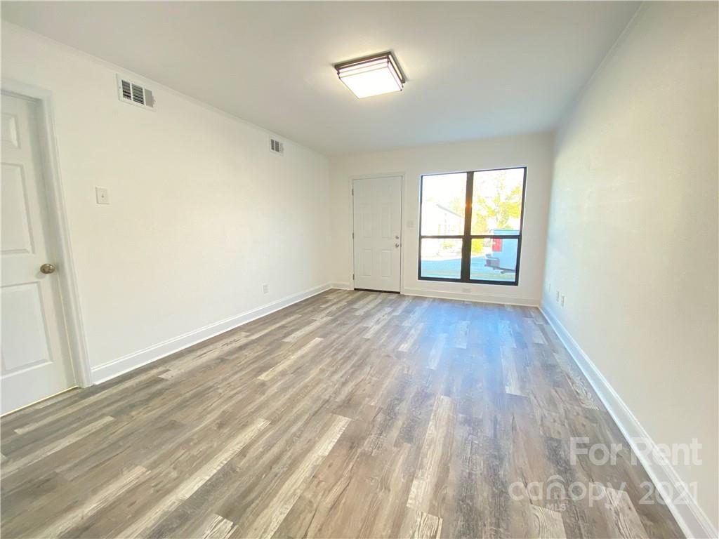 621 Stallings Road, Unit A Matthews, NC 28104 - Photo 9 of 10 an empty room with wooden floor and windows