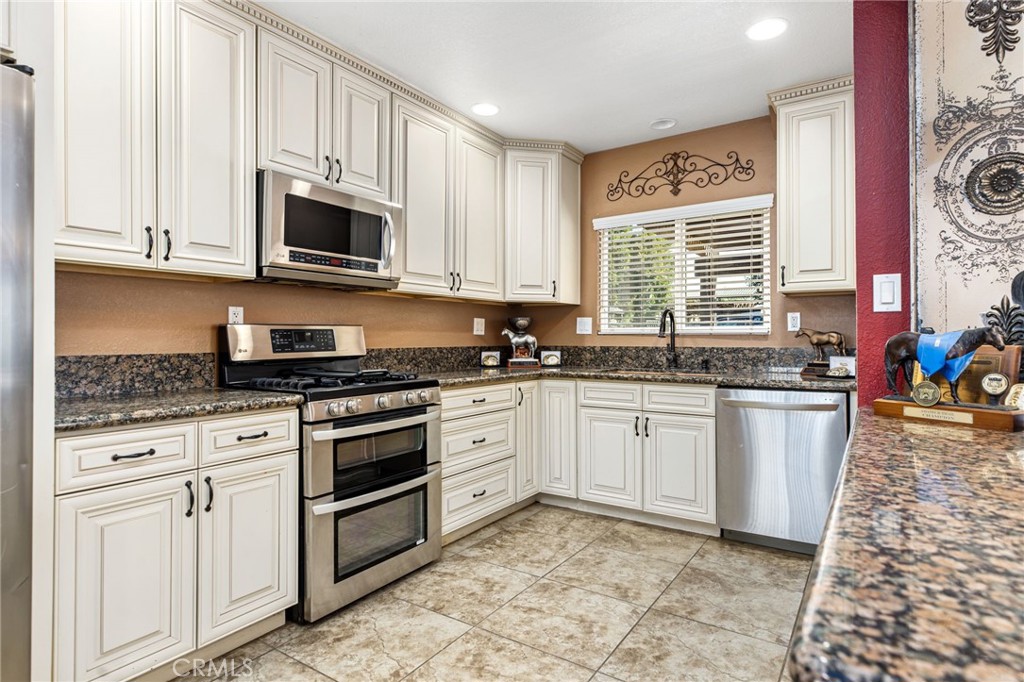 3243 Temescal Avenue Norco, CA 92860 - Photo 11 of 52 a white kitchen with stainless steel appliances granite countertop a stove a sink and a microwave