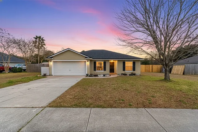 a view of a yard in front of a house with large trees