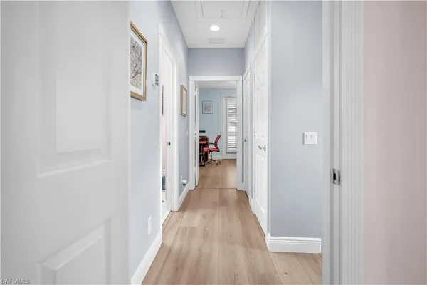 a view of a hallway with wooden floor and a bathroom