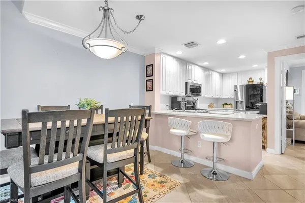 a kitchen with stainless steel appliances kitchen island granite countertop a dining table chairs and a refrigerator