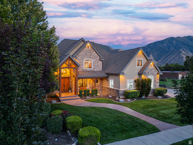 687 South 2080th Street East Springville, UT 84663 - Photo 90 of 149 Stone and stucco exterior featuring a prominent gabled entry with timber accents, a concrete pathway, a manicured lawn, and mature landscaping