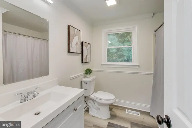 a bathroom with a toilet a sink a mirror and a window