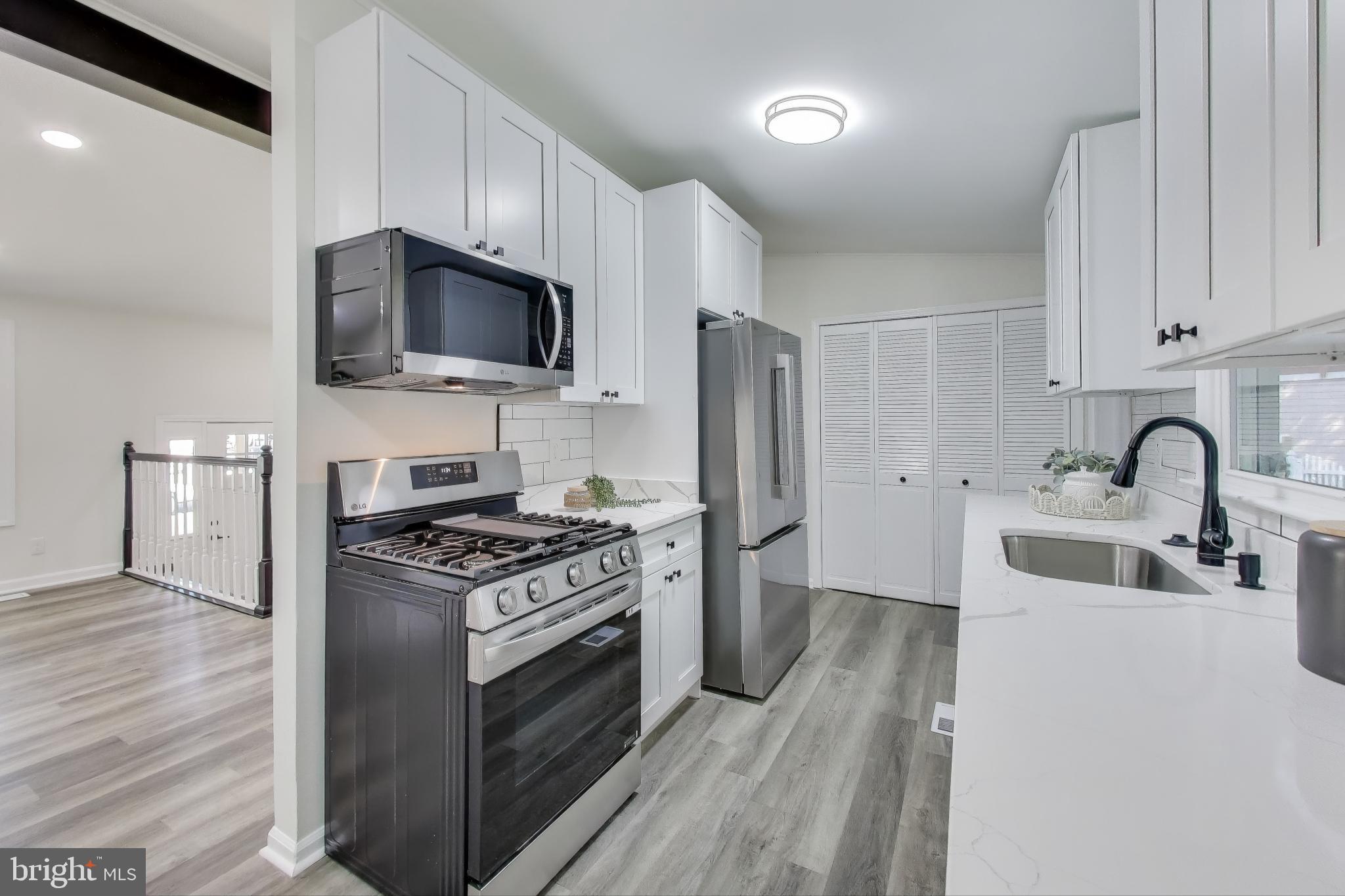 18905 Red Oak Lane Triangle, VA 22172 - Photo 10 of 38 a kitchen with stainless steel appliances a sink a stove top oven a refrigerator cabinets and a dining table with wooden floor
