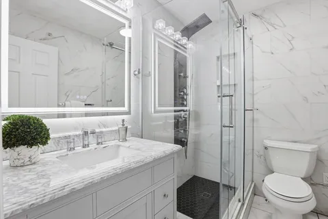 a bathroom with a granite countertop sink toilet and shower
