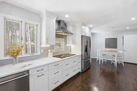 a kitchen with stainless steel appliances sink stove refrigerator and wooden floor
