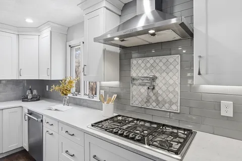 a kitchen with stainless steel appliances a stove and white cabinets