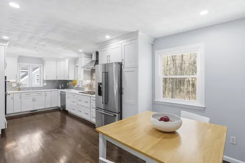 a kitchen with a sink a stove a refrigerator and white cabinets with wooden floor
