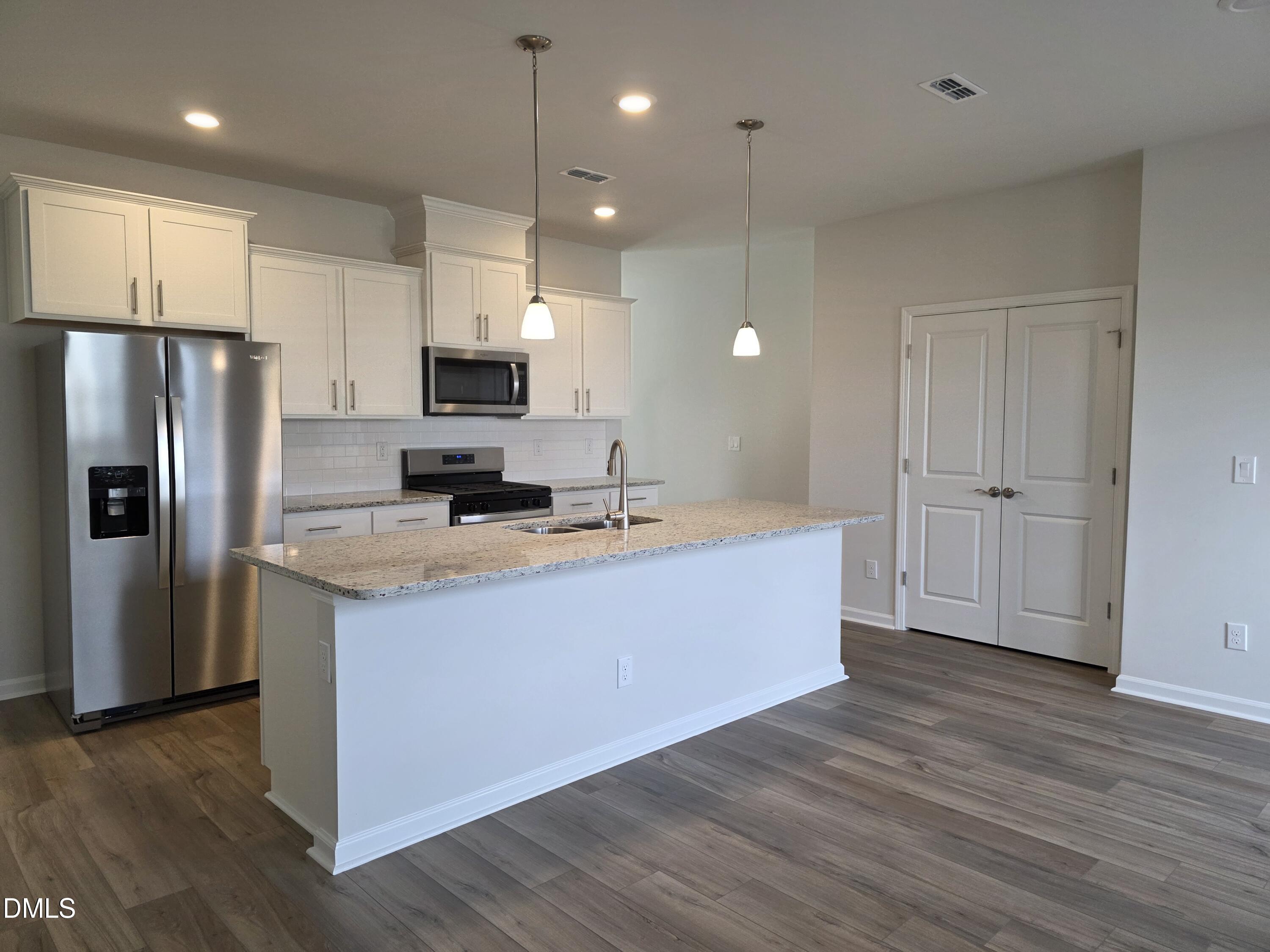 2540 Olive Chapel Road Apex, NC 27502 - Photo 6 of 27 a large kitchen with stainless steel appliances granite countertop a stove a refrigerator a sink a microwave and wooden floor