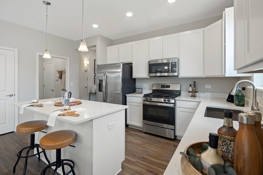 25612 West Springview Drive Plainfield, IL 60586 - Photo 3 of 23 a kitchen with stainless steel appliances kitchen island granite countertop a refrigerator a stove a sink a dining table and chairs with wooden floor