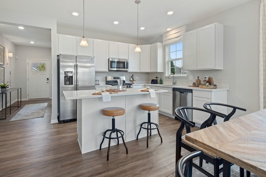 25612 West Springview Drive Plainfield, IL 60586 - Photo 4 of 23 a kitchen with stainless steel appliances granite countertop a dining table chairs stove refrigerator and cabinets