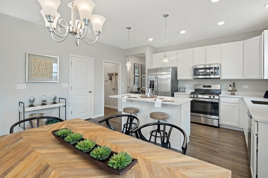 25612 West Springview Drive Plainfield, IL 60586 - Photo 7 of 23 a kitchen with stainless steel appliances granite countertop a sink a stove a dining table and chairs with wooden floor