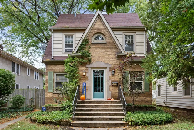 a view of a house with a yard plants and a large tree