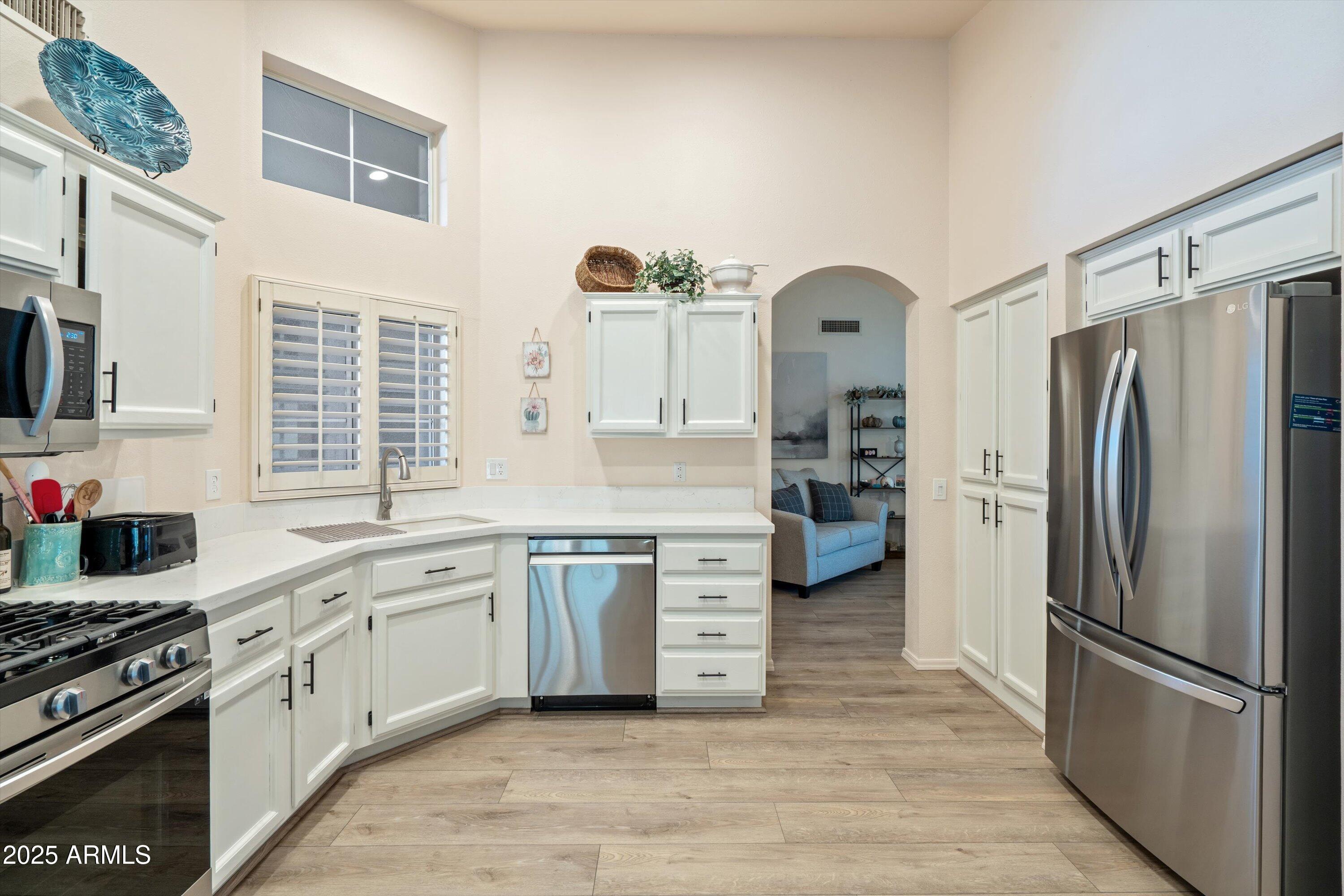 15415 West Merrell Street Goodyear, AZ 85395 - Photo 6 of 33 a kitchen with white cabinets and stainless steel appliances