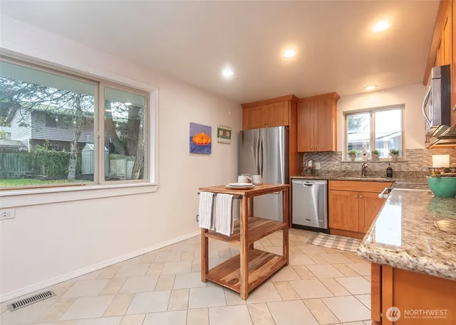 a kitchen with stainless steel appliances granite countertop a stove a sink and a refrigerator