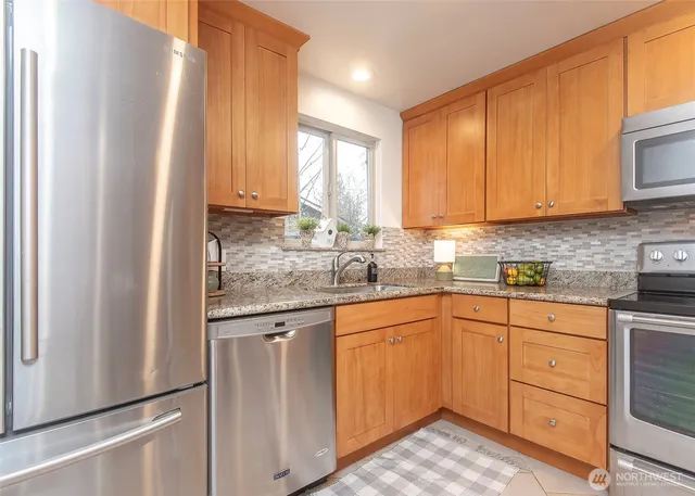 a kitchen with granite countertop wooden cabinets stainless steel appliances a sink and a window