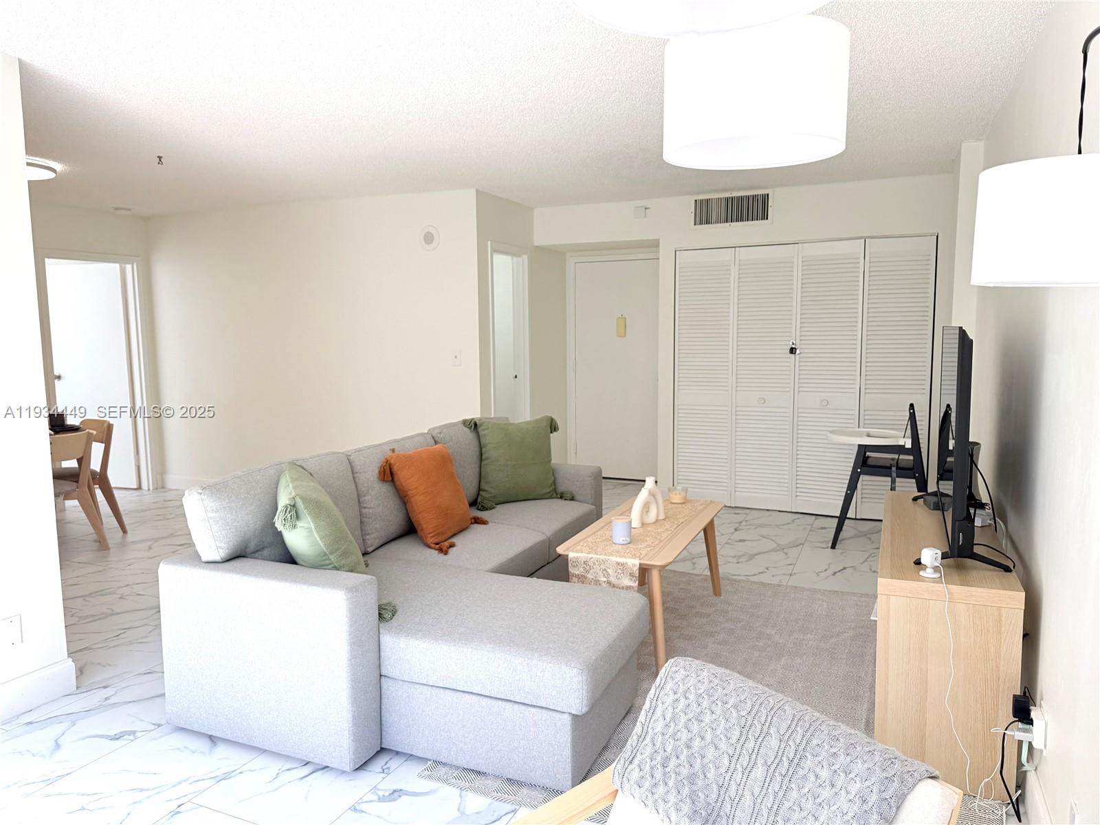 16909 North Bay Road, Unit 519 Sunny Isles Beach, FL 33160 - Photo 2 of 11 a living room with furniture a sink and a flat screen tv