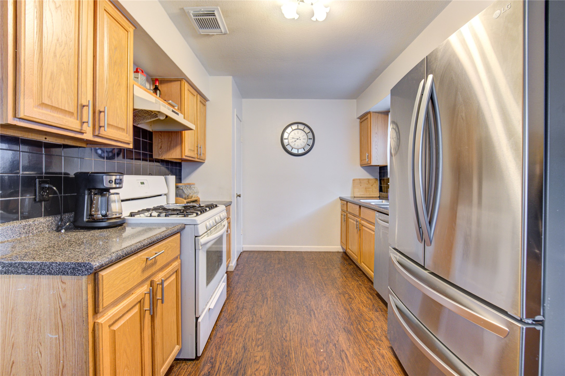 1403 Packsaddle Lane Baytown, TX 77521 - Photo 10 of 19 a kitchen with stainless steel appliances granite countertop a refrigerator a stove and a sink with wooden floor