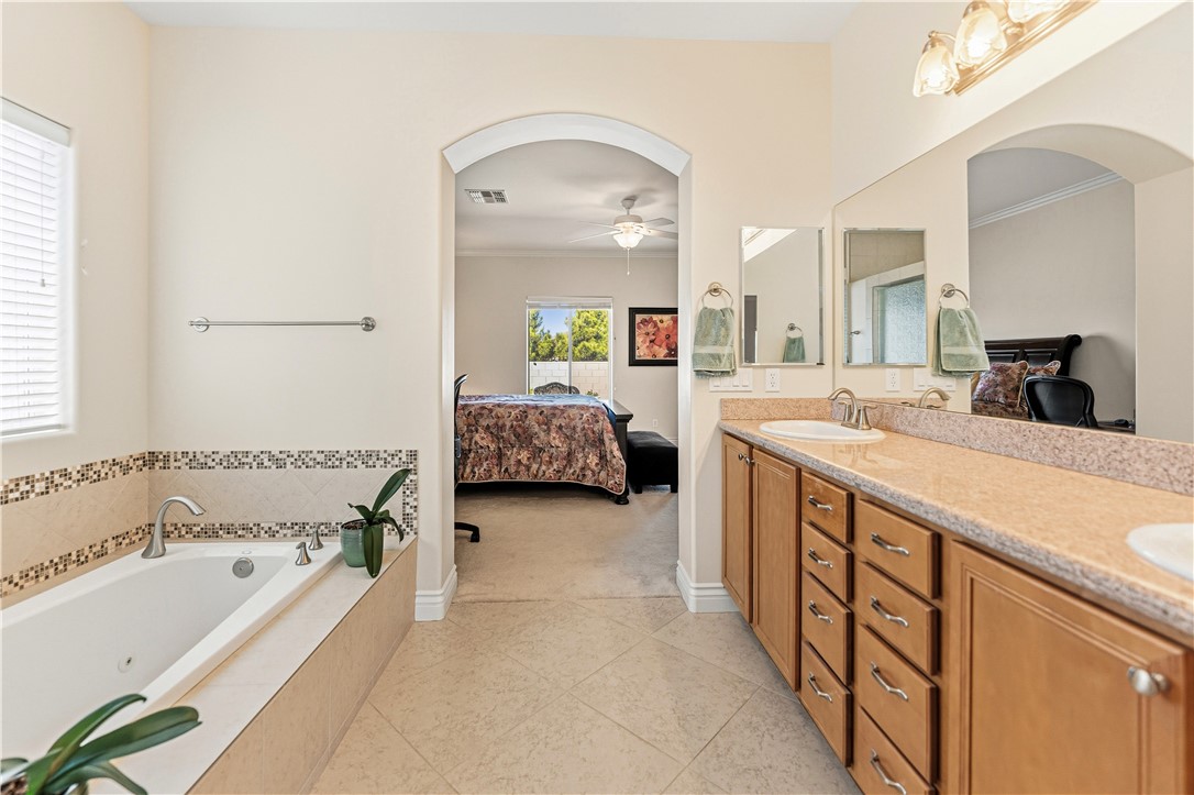3315 Rainbow Mine Road Kingman, AZ 86401 - Photo 23 of 54 The property features a bathroom with a built-in tub, a tile surround, and a window with blinds