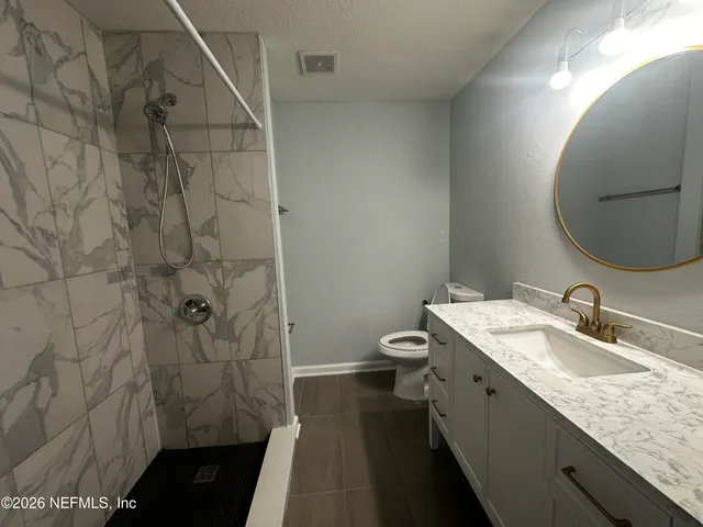 a bathroom with a granite countertop sink toilet and shower