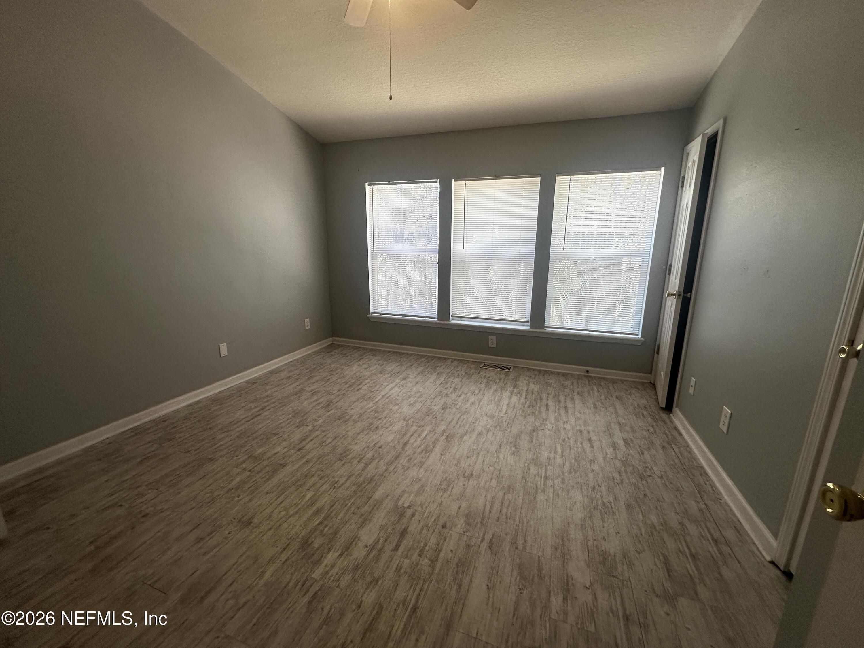 3548 Lone Tree Lane Jacksonville, FL 32216 - Photo 9 of 10 an empty room with wooden floor and windows
