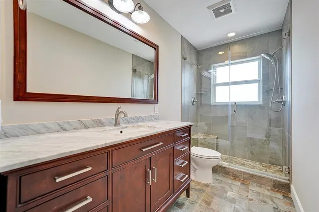 a bathroom with a granite countertop sink toilet and shower