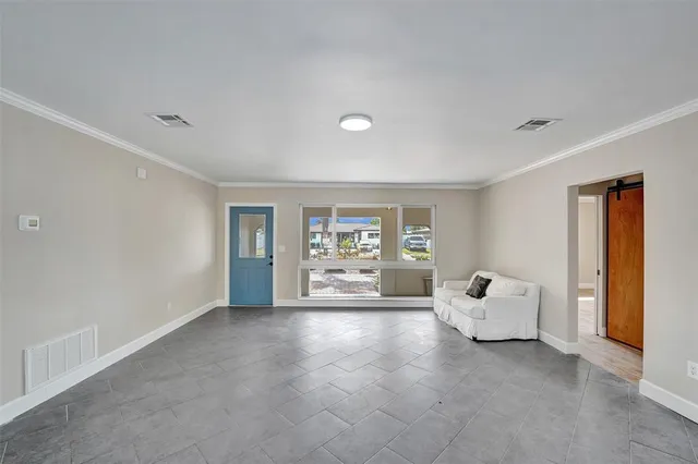 a view of an empty room with a window and a kitchen