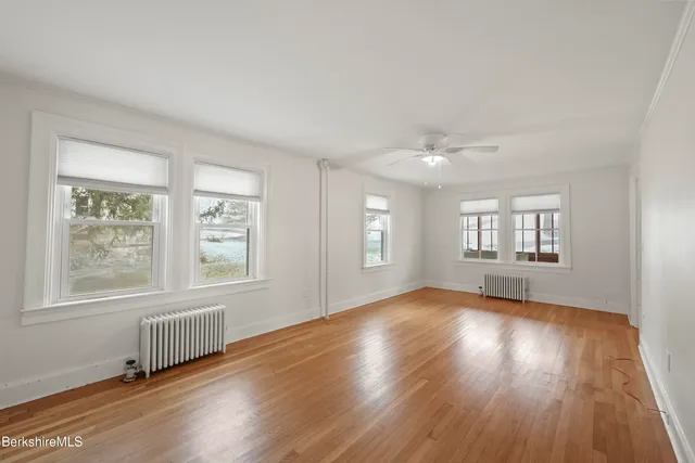 an empty room with wooden floor and windows