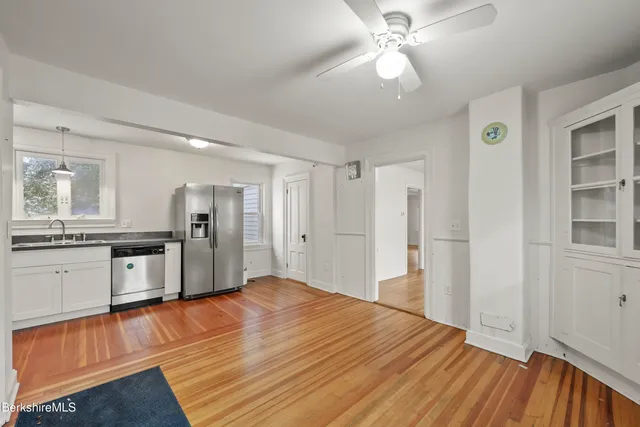 a large white kitchen with granite countertop a refrigerator and microwave