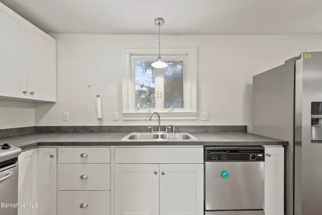 a kitchen with a sink a stove a refrigerator and white cabinets