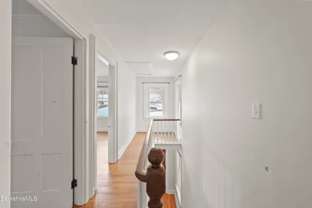 a view of a hallway to a livingroom with wooden floor and furniture