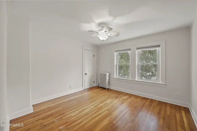 a view of empty room with wooden floor and fan