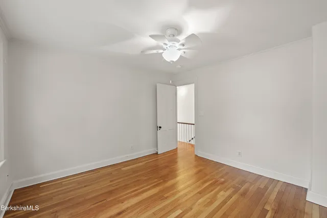a view of a room with wooden floor and ceiling fan
