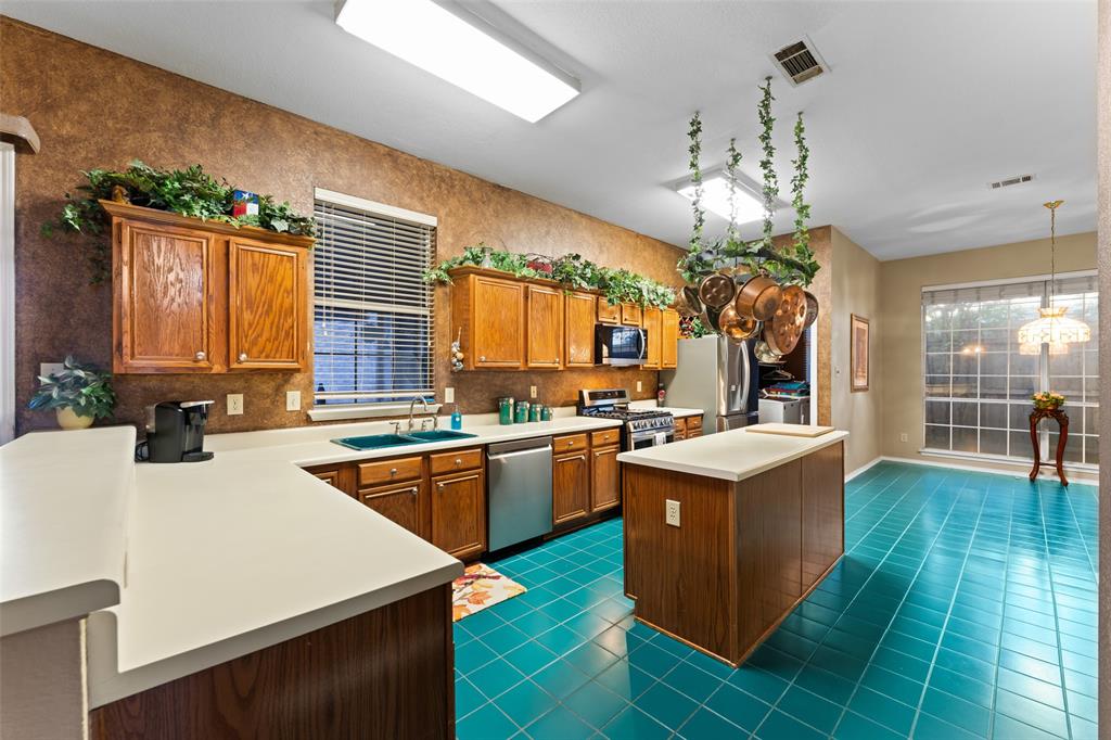 5509 Allen Lane Rowlett, TX 75088 - Photo 9 of 34 Kitchen with brown cabinets, dark tile patterned floors, appliances with stainless steel finishes, light countertops, and a kitchen island