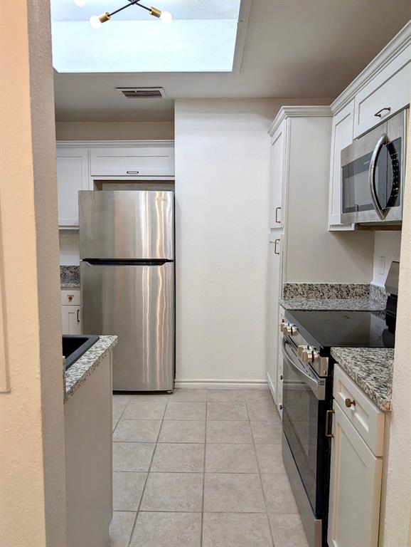 12680 Hillcrest Road, Unit 4101 Dallas, TX 75230 - Photo 12 of 37 Contemporary kitchen featuring a skylight, light-toned cabinetry, stainless steel appliances, and granite countertops