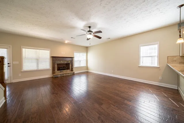 an empty room with windows fireplace and wooden floor