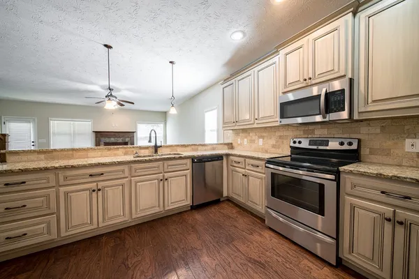 a kitchen with stainless steel appliances granite countertop a stove a sink and a microwave
