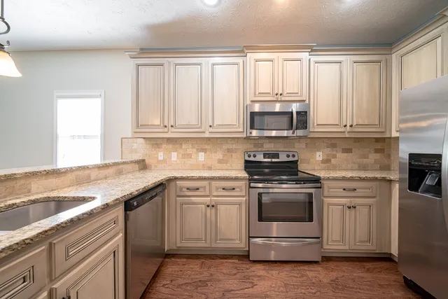a kitchen with granite countertop a stove sink and microwave