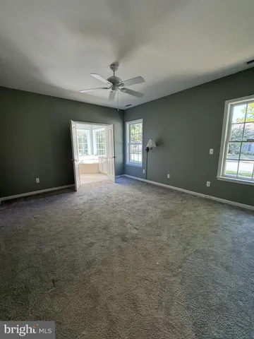 an empty room with windows and ceiling fan